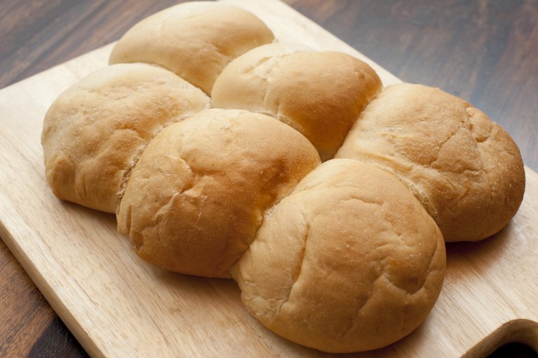 Photo of tasty fresh cooked buns on wooden board