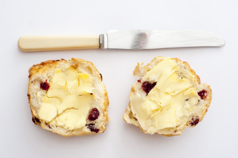 Still life of two sandwiches with butter and dried berries, knife. Isolated, from above