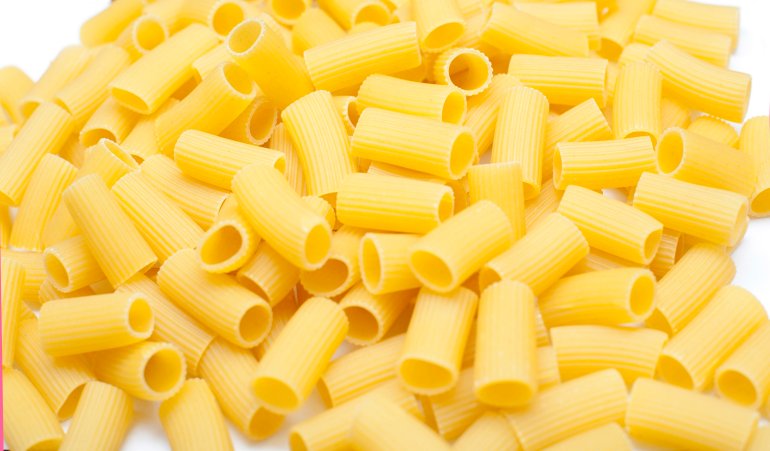 Close up background view of uncooked dried tubes of rigatoni pasta used as an ingredient in healthy Italian cuisine