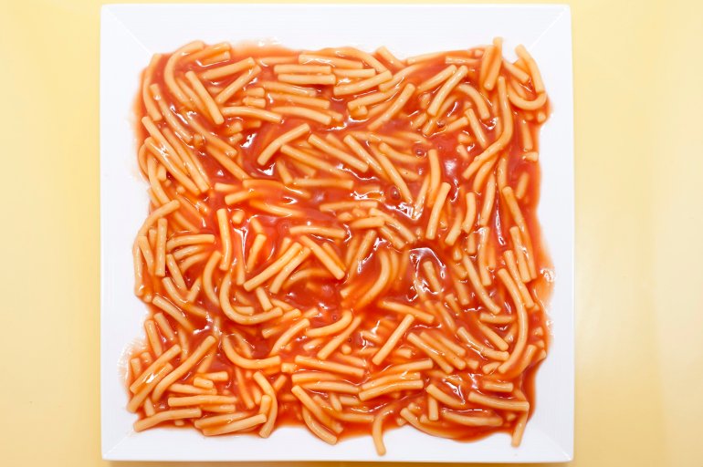 Overhead view of a square plate of tinned spaghetti pasta in tomato sauce for a quick nourishing meal