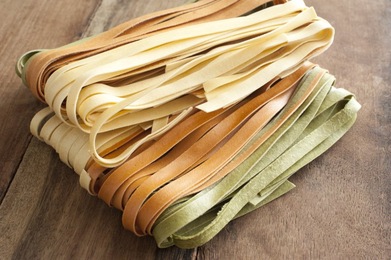 Homemade dried tagliatelle noodles in three varieties, plain, green and brown, for use as an ingredient in Italian or Mediterranean cuisine, high angle view