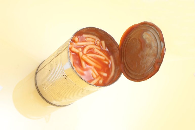 High angle view of an unlabelled open tin of canned spaghetti or noodles in tomato sauce
