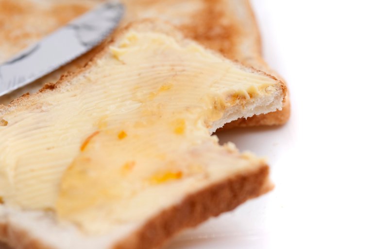 Slice of white buttered toast with a bite taken out of one corner, close up view