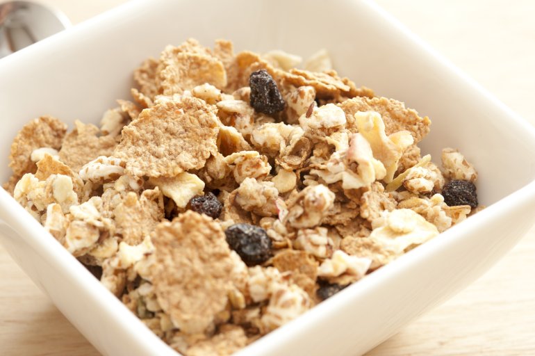 Delicious healthy breakfast muesli in a bowl with assorted cereals, chopped nuts and dried raisins and fruit, close up view