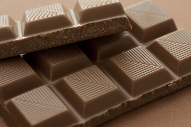 Bar of milk chocolate with pattern detail on the individual squares of converging lines in a close up view