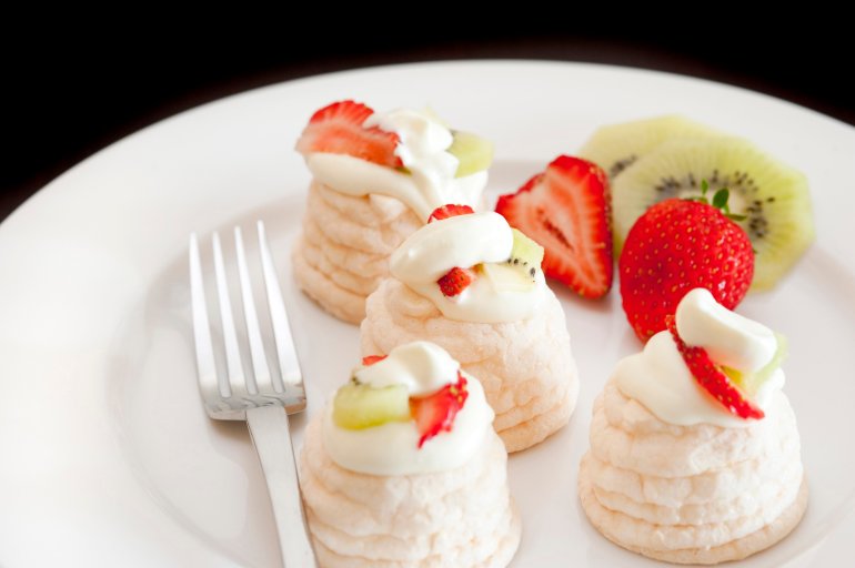 Serving of crisp meringue cones filled with whipped cream and fresh fruit for a healthy dessert