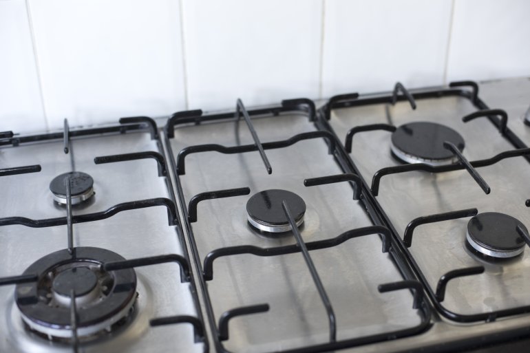 High angle view of superior quality gas range placed against a white tiled wall