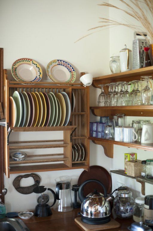 Country kitchen with glassware and crockery displayed on open wooden shelves and small appliances on a wooden counter