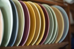 Assortment of colored clean dinner plates in rack