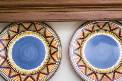 Two colorful patterned plates on a shelf