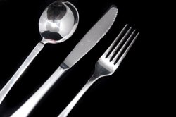 Clean metal knife, fork and spoon on black