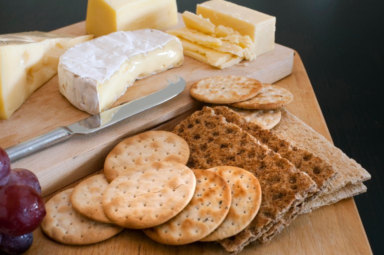 Cheese platter with assorted cheeses served as an appetizer with water biscuits and wheat crackers on a buffet table