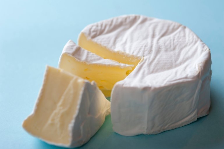 Round soft brie cheese with a wedge removed, closeup high angle view