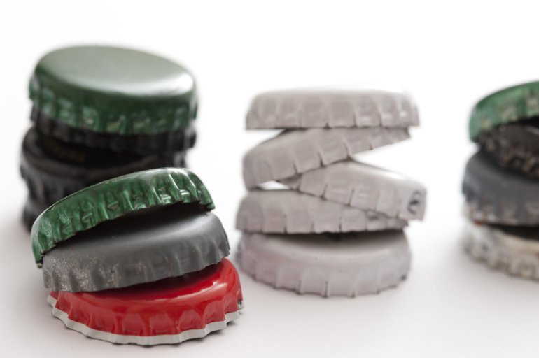 a stack of beer bottle tops on white background