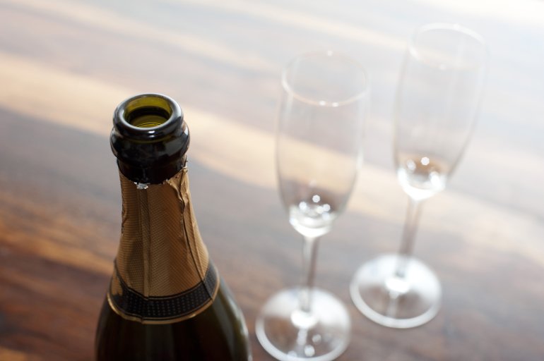 Opened champagne with a close up view of the neck of the de-corked bottle with two empty elegant flutes alongside for a romantic celebration