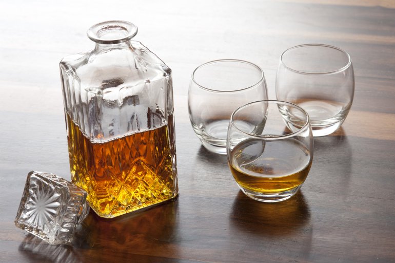 A glass wiskey decanter and glasses on a wooden table