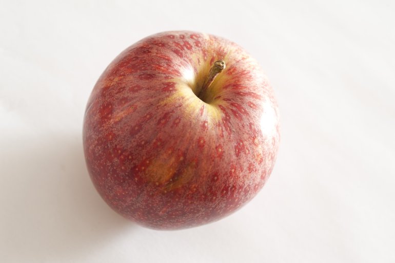 Fresh red apple on a white background viewed from above with focus to the stalk
