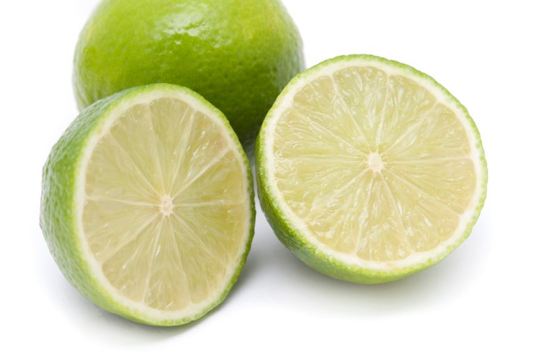 Close up of halved and whole fresh organic limes showing the juicy acidic pulp used as a flavouring in cooking