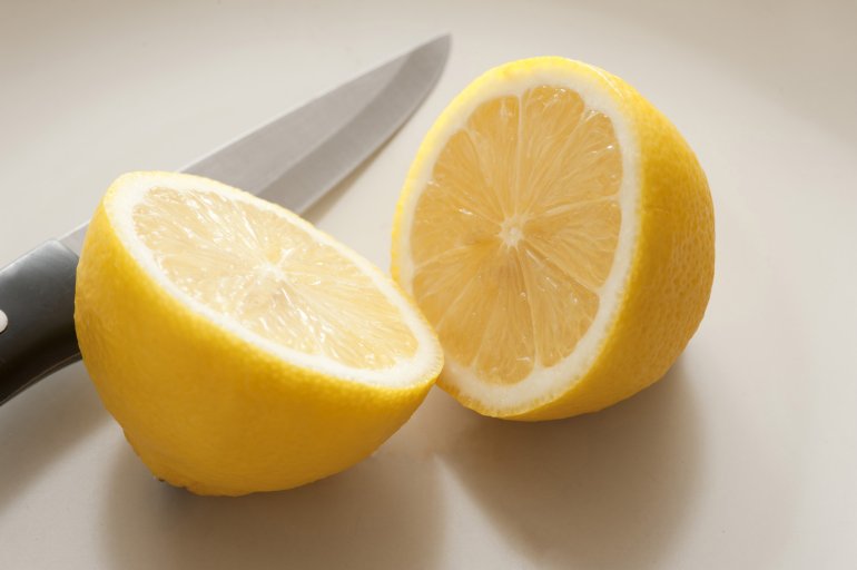 Close-up of cut lemon and knife on white table
