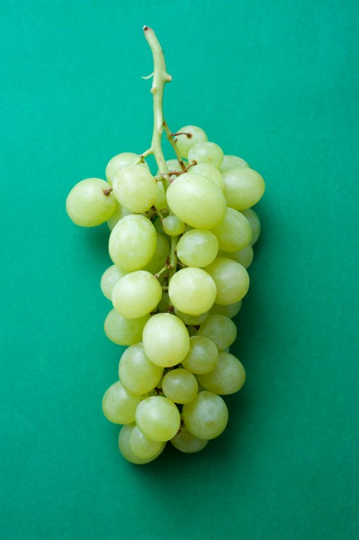 Fresh tasty green grapes (muscat variety), close-up on green background