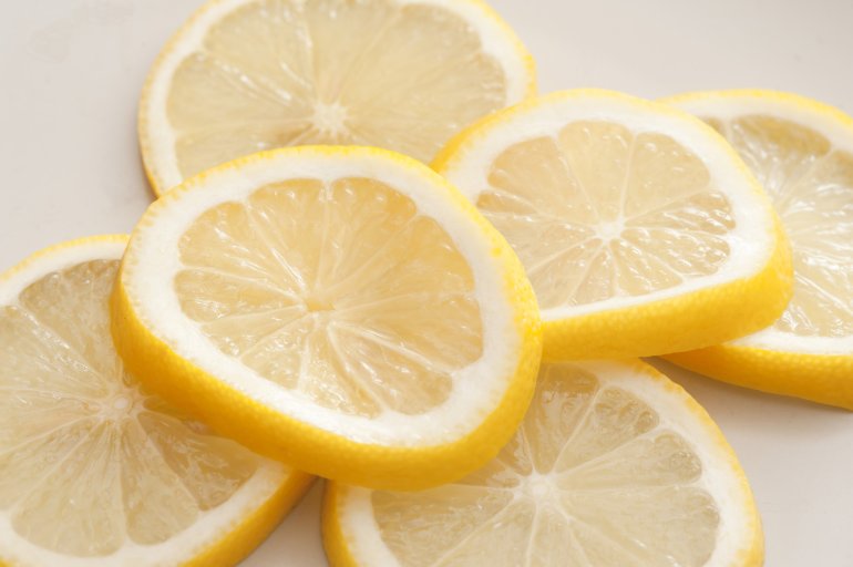 Heap of fresh ripe juicy lemon slices on white for use as a garnish in drinks and food, close up view