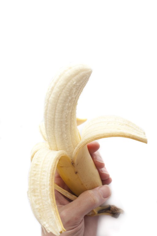 A hand holdng a peeled banana on white backdrop