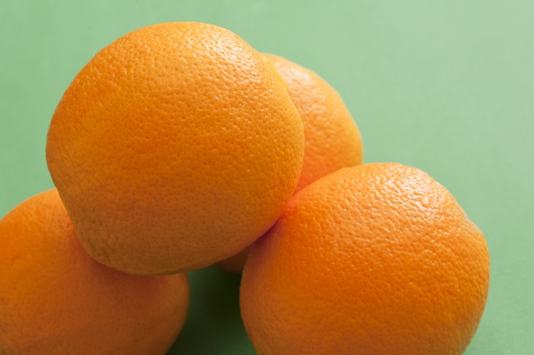Close-up of several oranges on green background