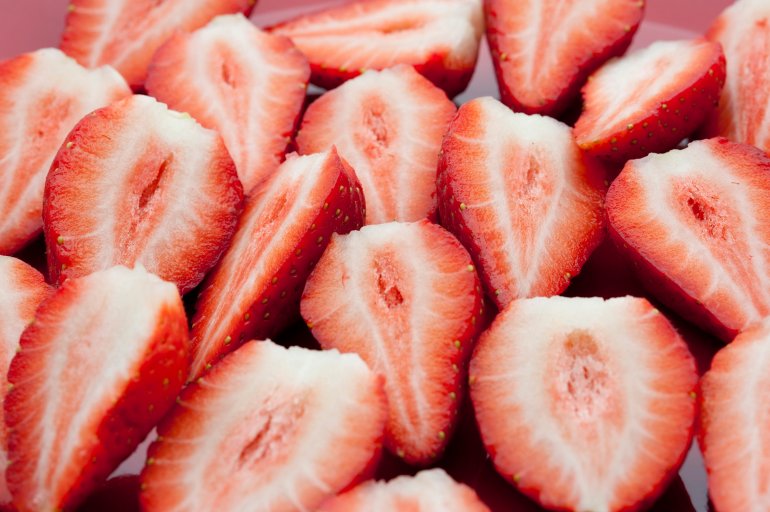 Background of sliced halved fresh strawberries showing the sweet tasty pulp prepared for a delicious dessert or ingredient in a meal