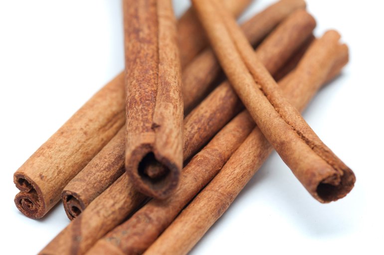 Close up detail of rolled cinnamon sticks used as a spice and condiment in cooking over a white background