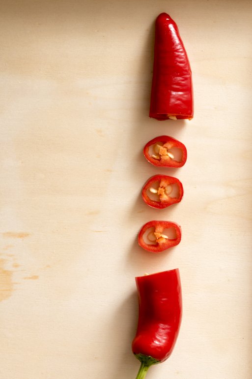 Red hot chilli pepper side border on a wooden background with copy space showing the centre section chopped into cross sections
