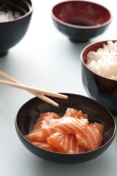 Fresh salmon dinner with chopsticks in black bowl