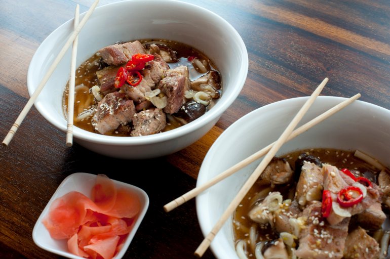 Japanese ramen, or noodles served in a broth garnished with vegetables and meat, served in two bowls with chopsticks