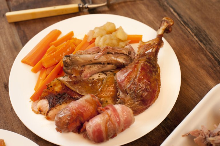 Delicious plated roast turkey dinner with vegetables to celebrate Christmas or Thanksgiving in a close up view on a wooden table