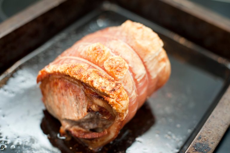 Crisp pork crackling on a roll of oven roasted pork in a grill pan