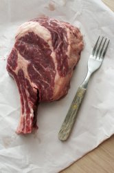Bone-in thick juicy raw ribeye beef steak