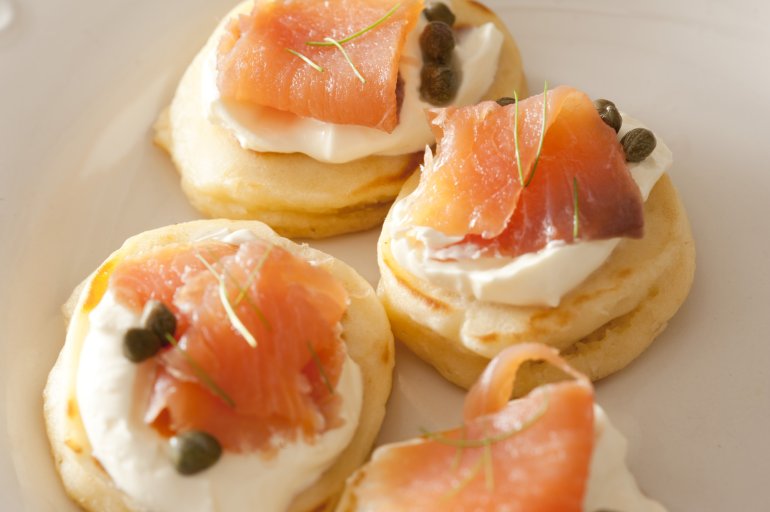 Selective focus cropped close up on lox biscuit snacks topped with capers and white sour cream or cheese