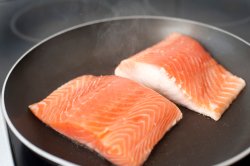 Two fresh salmon fillets in a frying pan