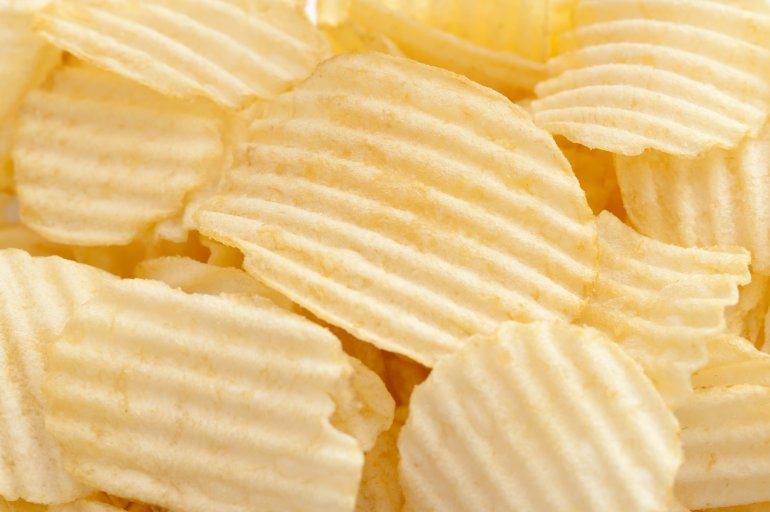 Background texture of crinkle cut crisps or potato chips in a full frame overhead view for a tasty snack or dip accompaniment