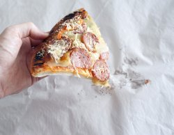 Hand holding limp pepperoni pizza slice
