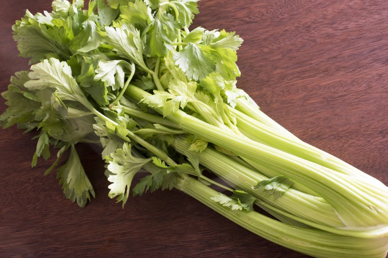 Bunch of fresh green celery stems and leaves on a wooden table, a healthy crunchy snack or salad ingredient