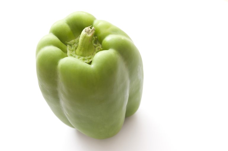 Fresh whole raw green bell pepper, sweet pepper or capsicum on a white background with copyspace, high angle view