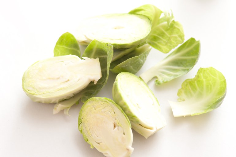A close up of sliced, prepared brussel sprouts on white background with copy space.