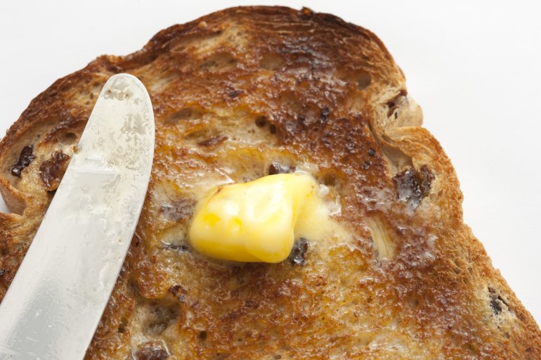 Close-up of tasty slice of bread with raisin covered with melting butter
