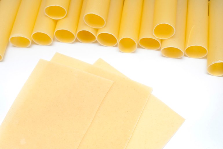 High angle view of uncooked Italian cannelloni tubes and lasagne pasta in sheets made from dried durum wheat dough