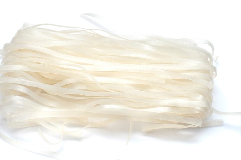 Bundle of rice noodles made from dried rice flour , often used as a gluten free alternative to traditional pasta, on white