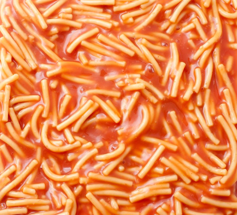 Background of canned spaghetti or noodles in tomato sauce, a quick snack and a favourite of children