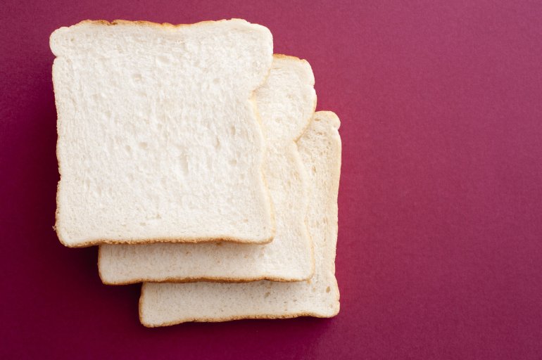 Photo of three white bread slices against of purple background