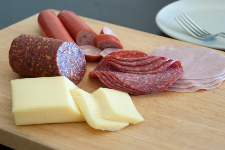 Protein rich German breakfast with sliced ham, salami and sausage and portions of cheese on a wooden platter