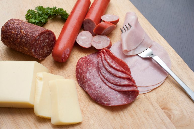 Wholesome traditional German breakfast with assorted spicy sausages, salami and cold meat accompanied by slices of cheese served on a wooden chopping board