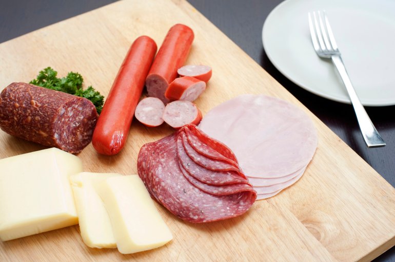 High angle view of a traditional german breakfast on a wooden board with sliced cold meats including spicy salami and sausage served with cheese for a wholesome meal